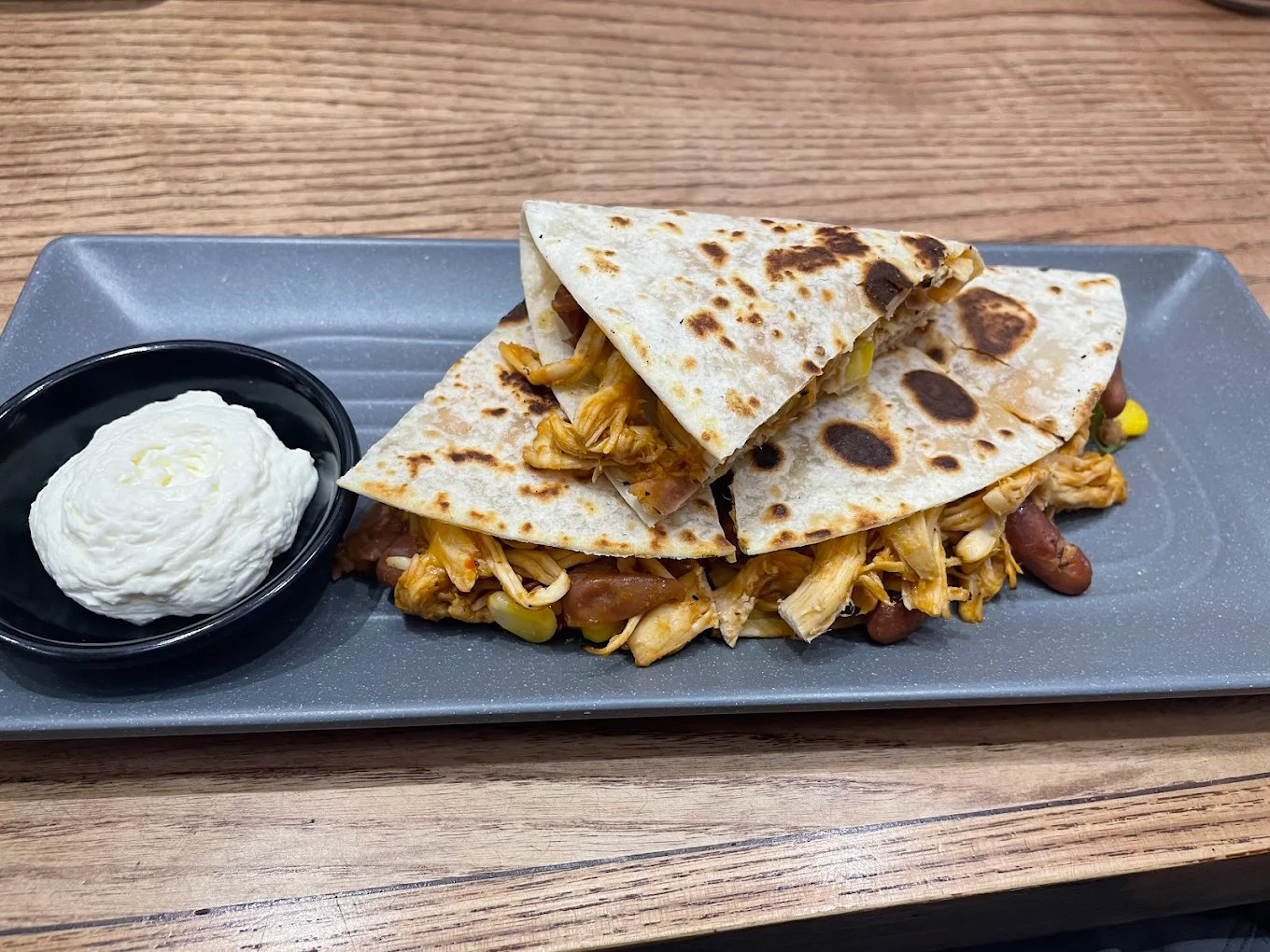 A crispy Quesadilla filled with flavorful meat and vegetables, served with salsa and sour cream